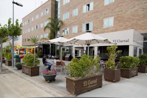 a man sitting at a cafe with tables and umbrellas at Hotel Rull in Deltebre