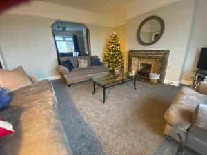 a living room with a christmas tree and a couch at Amazing views across the Moray Firth, Private Suntrap Patio, 300m from the Beach, off street parking! in Nairn