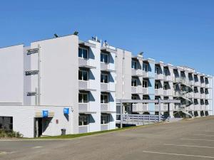 een groot wit appartementencomplex met een parkeerplaats bij ibis budget Angoulême Nord in Champniers