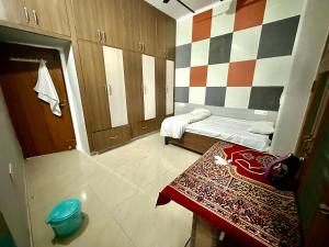 a small room with a bed and a checkerboard wall at Vardan Homes in Mathura