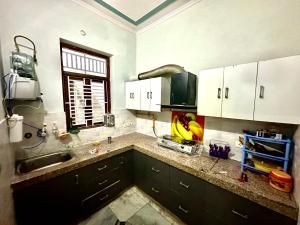 a kitchen with white cabinets and a sink and a window at Vardan Homes in Mathura