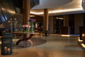 un vestíbulo con una mesa con jarrones de flores. en Infinity Hotel & Conference Resort Munich en Unterschleißheim