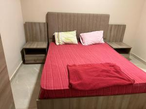 1 cama con manta roja y 2 almohadas en Alexandria BLUE Wave, en Alejandría