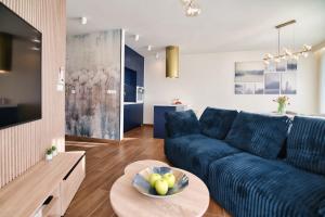 Una sala de estar con un sofá azul y una mesa. en Laguna Beskidów Resort - Apartament A15, en Zarzecze