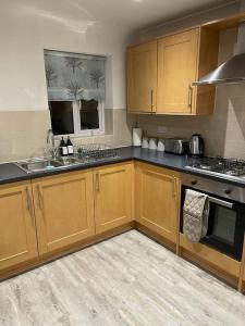 a kitchen with wooden cabinets and a stove top oven at Jdb Romford Apt - Cosy 2 Bedroom with parking in Harold Wood