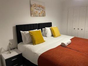 a bedroom with two beds with yellow and white pillows at Jdb Romford Apt - Cosy 2 Bedroom with parking in Harold Wood