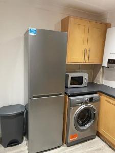 uma cozinha com um frigorífico e uma máquina de lavar roupa em Jdb Romford Apt - Cosy 2 Bedroom with parking em Harold Wood