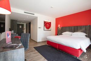 um quarto com uma parede vermelha, uma cama e uma secretária. em Hôtel du Bois Blanc Domaine d'Epeyssoles Georges Blanc em Vonnas