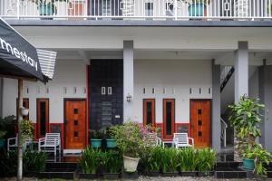 ウォノソボにあるRedDoorz at Jalan Dieng 3のオレンジと白の扉と植物のある建物