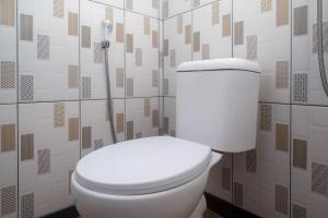 a white toilet in a bathroom with geometric wallpaper at RedDoorz at Jalan Dieng 3 in Wonosobo