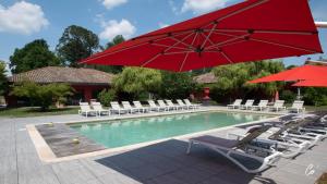 a swimming pool with chairs and a red umbrella at Hôtel du Bois Blanc Domaine d'Epeyssoles Georges Blanc in Vonnas