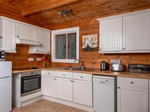 a kitchen with white cabinets and a wooden ceiling at 3 bed in Clyro BN141 in Clyro