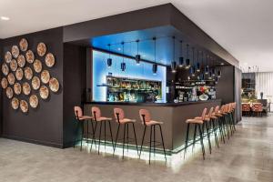 un bar avec une rangée de tabourets roses dans l'établissement Vienna House by Wyndham zur Bleiche Schaffhausen, à Schaffhouse