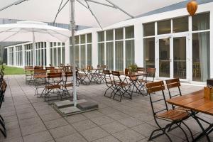an outdoor patio with tables and chairs and umbrellas at Vienna House Easy by Wyndham Landsberg in Landsberg am Lech