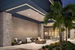 a lobby with chairs and tables and a palm tree at Home2 Suites Orlando Southeast Nona in Orlando