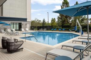 einen Pool mit Stühlen und Sonnenschirmen auf einer Terrasse in der Unterkunft Home2 Suites Orlando Southeast Nona in Orlando