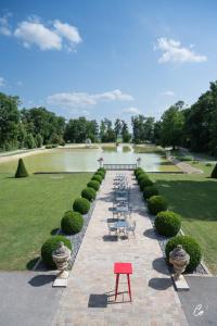 a garden with a pond with a red table and chairs at Hôtel du Bois Blanc Domaine d'Epeyssoles Georges Blanc in Vonnas