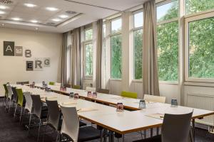 a row of tables and chairs in a room with windows at Vienna House Easy by Wyndham Amberg in Amberg