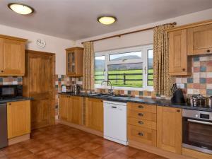 a large kitchen with wooden cabinets and a window at 3 Bed in Brecon Town BN037 in Llanspyddid