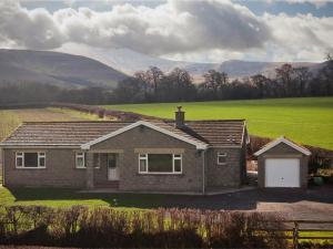 a house in a field with mountains in the background at 3 Bed in Brecon Town BN037 in Llanspyddid