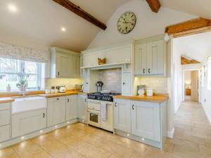 a kitchen with white cabinets and a clock on the wall at 2 Bed in Audlem 81106 in Audlem
