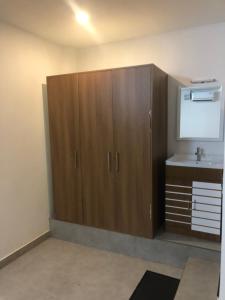 a bathroom with a sink and a large wooden cabinet at Chittinappilly Cottage in Angamaly