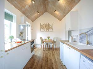 cocina con armarios blancos y techo de madera en 1 Bed in Nr. Rothbury 82147 en Longhorsley