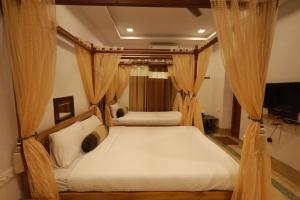 a bedroom with two beds with curtains and a television at ROYAL STAY VINTAGE in Madurai