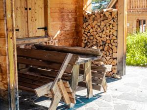 德哥米斯的住宿－Alpin-Hütten auf der Turracherhöhe - Haus Fuchs by S4Y，木凳,旁边堆着一堆木柴