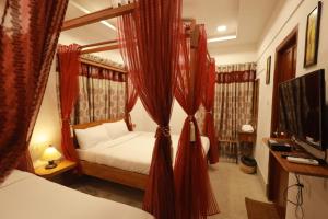 a bedroom with a bed with red curtains and a television at ROYAL STAY VINTAGE in Madurai