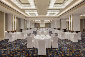 Indore Marriott Hotel في إندوري: قاعة اجتماعات مع طاولات بيضاء وكراسي بيضاء