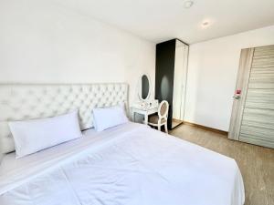 een slaapkamer met een groot wit bed en een tafel bij Town Sukhumvit 71 in Bangkok