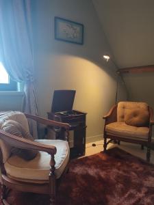 een woonkamer met 2 stoelen en een piano bij Via Caput in Lokeren