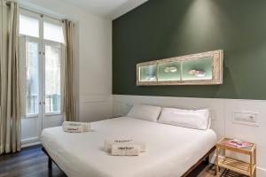 Un dormitorio con una cama blanca con una pared verde. en Enjoybcn Tallers Apartment, en Barcelona