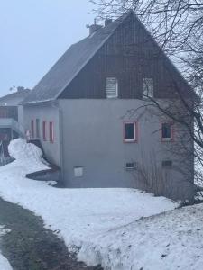 a white barn with snow on the side of it at Chata Na Rozcestí in Loučná pod Klínovcem