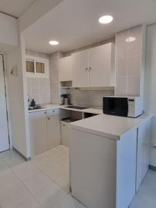 a large kitchen with white cabinets and a microwave at Jupiter2 Moderno estudio Parque La Paloma in Benalmádena