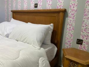 a bed with white pillows and a wooden head board at Anza SurfSide House in Agadir