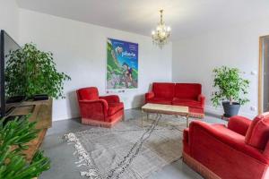a living room with red chairs and a tv at Villa de Lurp panorama spa 12 pers in Saint-Pastous