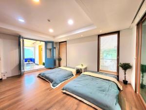 two beds in a large room with wood floors at Seochon Dalbit in Seoul