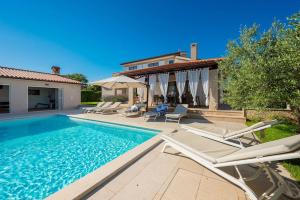 a swimming pool with chairs and a house at Villa Lana by IstriaLux in Vodnjan