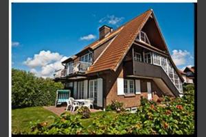 een groot huis met een tafel en een stoel in de tuin bij Südstrand 11 in Westerland