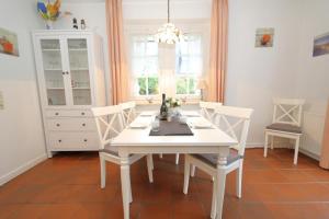 un comedor blanco con una mesa y sillas blancas en Südstrand 11 en Westerland