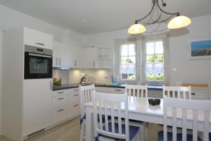 uma cozinha com armários brancos e uma mesa e cadeiras em Südstrand 3 em Westerland