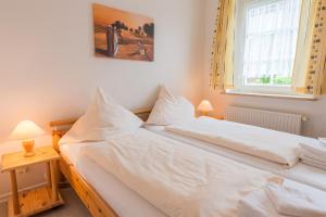 1 dormitorio con 1 cama con sábanas blancas y ventana en Südstrand 3 en Westerland