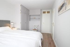 une chambre blanche avec un lit blanc et une chaise dans l'établissement Haus Metropol - App. 234 SWB, à Westerland