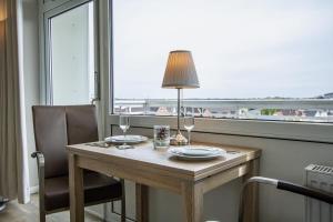 une table avec une lampe et deux verres devant une fenêtre dans l'établissement App. Preetz 32 OB, à Westerland