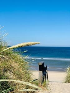 un banc sur une plage avec l'océan en arrière-plan dans l'établissement App. Preetz 32 OB, à Westerland
