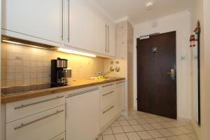 a kitchen with white cabinets and a brown door at Haus am Meer14 - App. 144 WB in Westerland
