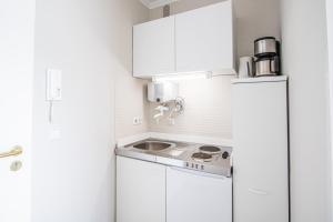 eine kleine weiße Küche mit einer Spüle und einem Kühlschrank in der Unterkunft App. Busch 45 in Westerland