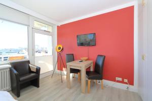 um quarto com uma mesa e cadeiras e uma parede vermelha em Dorow 48 WB em Westerland
